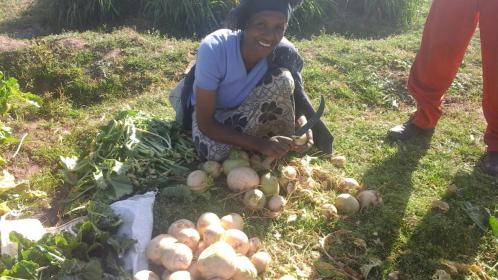 Woman smiling over freshly harvested crops in Ethiopia